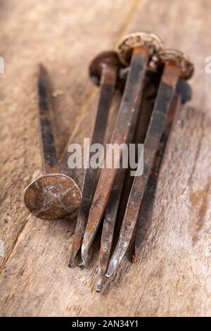 Vecchi chiodi arrugginiti su un banco di lavoro. Elementi in acciaio forgiato nella vecchia tecnologia per la giunzione di legno. Luogo - laboratorio di falegnameria. Foto Stock