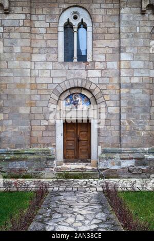 Dettagli colorati di un ingresso al monastero di Manasija con porte in legno, pareti in pietra e vetro blu sulle finestre Foto Stock