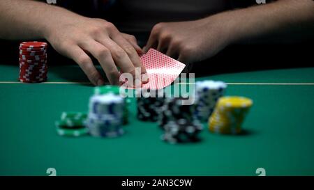 L'uomo le carte di controllo e il sollevamento, Bluff durante il torneo di poker, possibilità di vincere Foto Stock