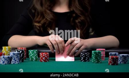 Donna controllando la sua combinazione di carte in gioco di poker al Casino, il gioco d'azzardo e dipendenza Foto Stock