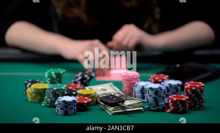 Addicted to gaming donna controllando la sua combinazione di carte nel poker, spreco di denaro Foto Stock