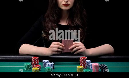 Donna giocatore controllando la sua combinazione di carte, bluff al casinò poker game Foto Stock