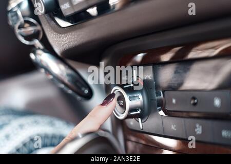 Modalità di trasporto. Auto elettrica donna interio pushingr ac e il pulsante di ventilazione sul quadro di comando close-up Foto Stock