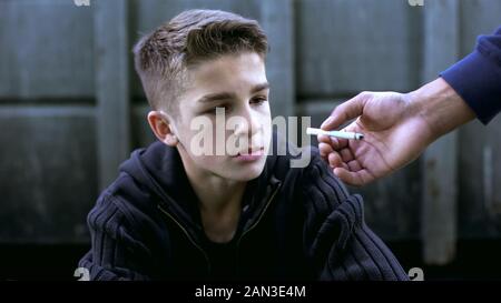 Ragazzo di imparare a fumare con il vecchio amico, cattiva influenza di vita di strada, tossicodipendenza Foto Stock