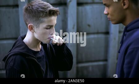 Teen Learning di fumare con il vecchio amico, cattiva influenza, la vita di strada, tossicodipendenza Foto Stock