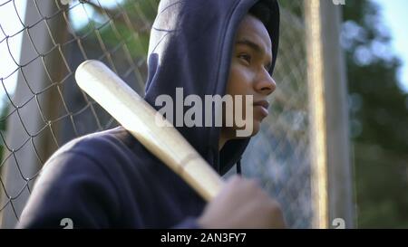 Afro-adolescente americano tenendo mazza da baseball, gioventù pista in ghetto, primo piano Foto Stock