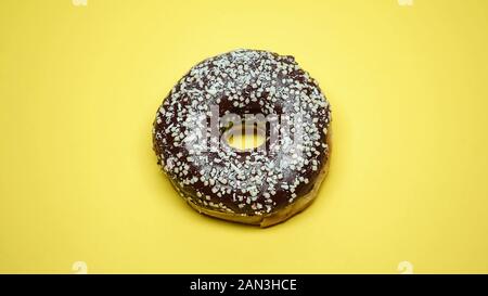 Al delizioso cioccolato ciambella su sfondo giallo, pasticceria, macro shot Foto Stock