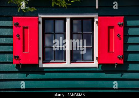 Rosso brillante persiane in legno in un verde parete in legno e nebbioso windows in una giornata di sole Foto Stock