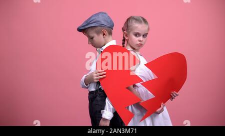 Offeso bambini giovane azienda pezzi rotti di cuore rosso, litigi, freno fino Foto Stock