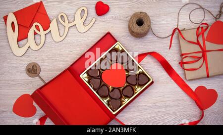 Regalo di San Valentino con scatola a forma di cuore di cioccolatini su sfondo di legno Foto Stock