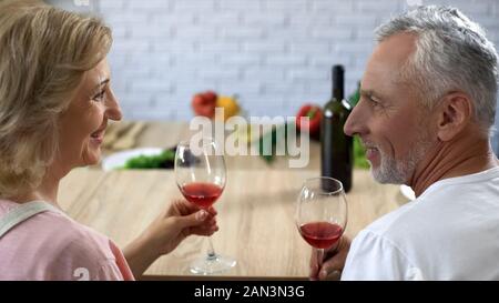 Romantica di età matura con bicchieri di vino alla data iniziale, matrimonio felice, aperitivo Foto Stock