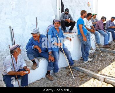 Le guide locali aspettano che i clienti possano percorrere i muli lungo il ripido sentiero acciottolato dalla città di Fira al porto di Santorini Grecia. Foto Stock