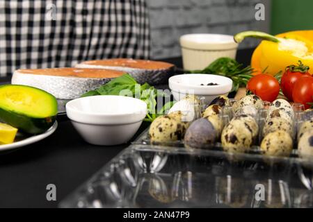 Un set di sana e bilanciata super cibo, uova in primo piano, salmone fresco, verdure, cereali e i dadi su uno sfondo nero. Vista superiore, laici piatta Foto Stock