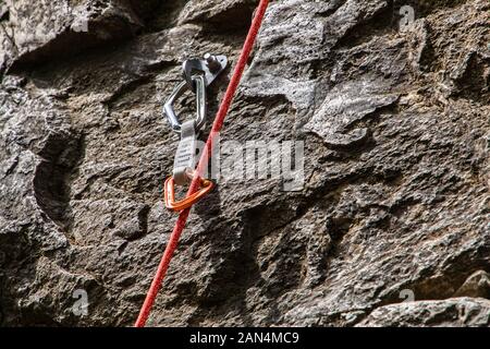 Una chiusura e una vista dettagliata di una sosta del dispositivo e corda dinamica fissata ad un robusto roccia calcarea. Professional arrampicata attrezzature in uso Foto Stock