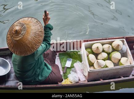 La donna a un mercato galleggiante vendita di noci di cocco Foto Stock