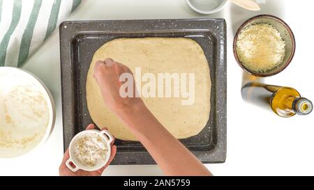 La cottura del pane di formaggio passo dopo passo. Topping di pasta di pane con sale di stagionatura. Close up, vista dall'alto, su sfondo bianco. Foto Stock