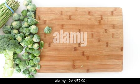 I cavoli di Bruxelles su un tagliere di legno, close up su sfondo bianco, vista dall'alto Foto Stock