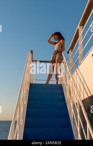 Ragazza teen in pantaloncini e tubo in piedi sulla scala superiore delle scale sul traghetto in Grecia Foto Stock