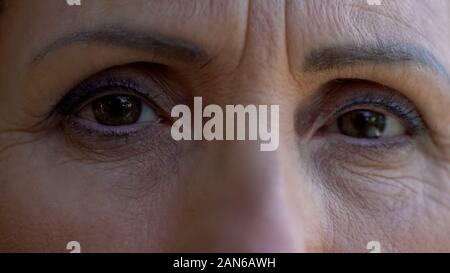 Extreme close-up di donna matura occhi tristi pensionati lady guardando nella telecamera Foto Stock