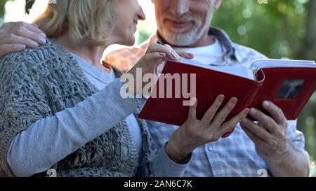 I genitori adulti ammirando le foto in album di famiglia ricordando la gioventù, momenti felici Foto Stock