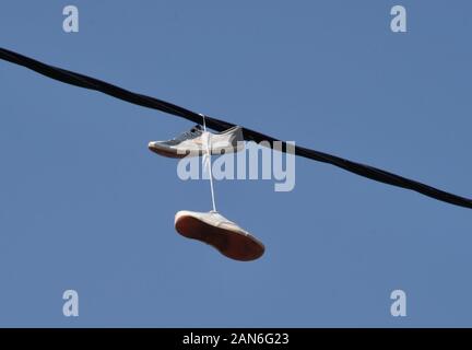 Scarpe attaccato ad un filo elettrico mediante i lacci Foto Stock