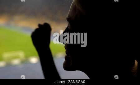 Donna felice fan fare il tifo per la squadra di calcio a vincere sul stadio affollato, emozione Foto Stock