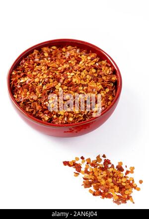 Hot Chili fiocchi in un colorato di rosso ciotola isolati verticali su sfondo bianco Foto Stock