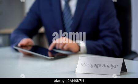 Ipoteca giovane analista lavora su tablet pc, analizzando il mercato immobiliare Foto Stock