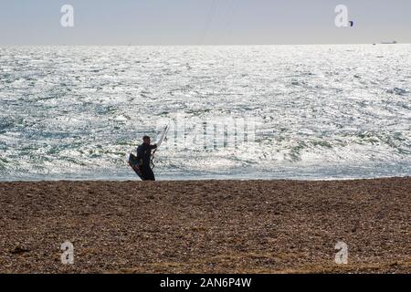 20 settembre 2019 un giovane uomo nel surf la preparazione di kiteboard le onde dalla spiaggia di ghiaia a Hayling Island in Hampshire sulla costa sud di Foto Stock
