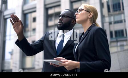 Architetti confrontare il progetto sul tablet con sito in costruzione, edificio alto Foto Stock