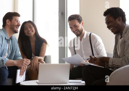 Sorridente diversi colleghi ridere cooperanti a briefing in ufficio Foto Stock