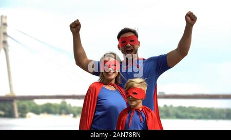 Famiglia allegra in superman costumi divertendosi, ingannare circa, tempo libero Foto Stock