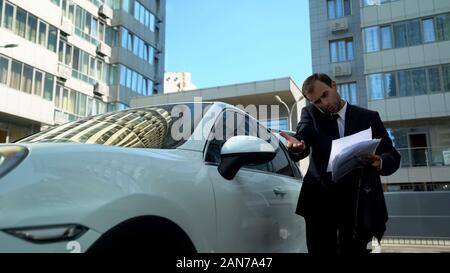 Imprenditore nervoso parlando al telefono con il segretario trovare gli errori nel documento Foto Stock