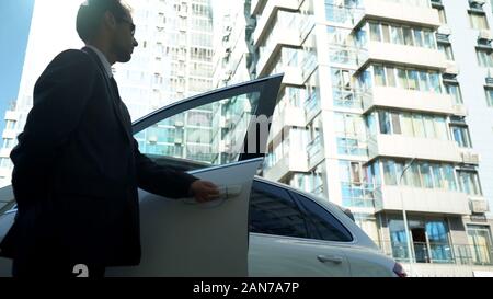 La guardia di sicurezza si apre le porte auto a lady boss, sicurezza per il candidato, vista dal basso Foto Stock