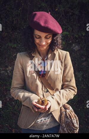 Donna in abbigliamento casual detiene un castagno sulle sue mani all'aperto Foto Stock