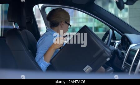 Business donna prendendo nella valigetta e uscire da auto parcheggiate vicino centro uffici Foto Stock