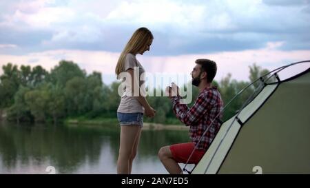 Giovane uomo propone la ragazza in foresta, fidanzamento romantico, felicità Foto Stock