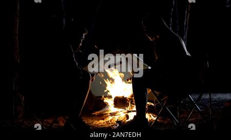 Amici grigliare salsicce su aprire il fuoco fiamma su rami di legno, resto Foto Stock