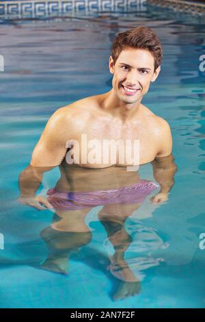 Felice l'uomo è in piedi sorridente nell'acqua della piscina Foto Stock