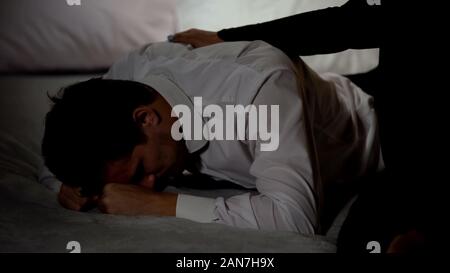 Uomo di piangere, femmina consolante di lui, il funerale della persona vicina, vittima della violenza Foto Stock