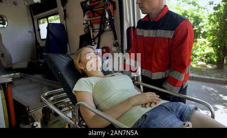 I paramedici che trasportano il paziente sulla barella in ambulanza, veloce guida qualificata Foto Stock