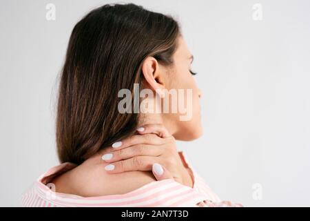 Vista posteriore della giovane donna che soffre di dolori al collo Foto Stock