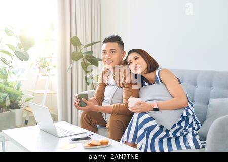 Amare Asian giovane seduto sul divano e godersi il tempo insieme Foto Stock