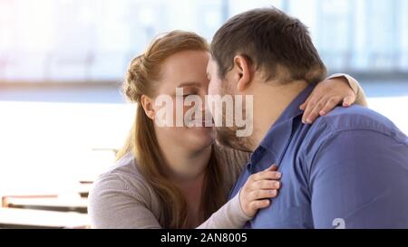 Dolce matura in amore nuzzling seduta sul banco di città, weekend insieme, vicinanza Foto Stock