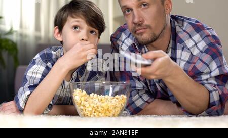 Società maschio di trascorrere del tempo insieme a guardare la tv e mangiare popcorn, paternità Foto Stock