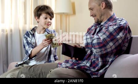 Piccolo figlio di padre chiedendo a dare più soldi di tasca, esigenze finanziarie, paternità Foto Stock