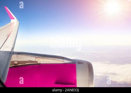 Ala economia della compagnia di volo aereo sopra le nuvole con un luminoso sole che splende su sfondo a mezzogiorno. A buon mercato aereo e biglietti di viaggio. Fast Foto Stock