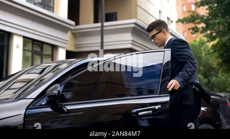 Bello lavoratore di ufficio sempre in nuove auto di lusso vicino al centro business, promozione Foto Stock