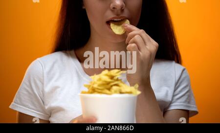 Ragazza di mangiare patatine, sapori artificiali in alimenti causare dipendenza, i rischi per la salute Foto Stock