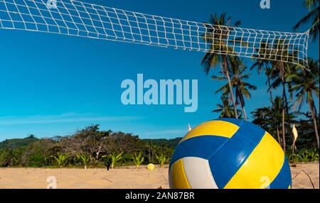 Il Beach Volley. Sfera di gioco sotto la luce del sole e cielo blu con rete da pallavolo sullo sfondo Foto Stock